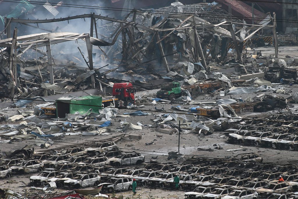 epa04882862 Rescuers search amidst many burnt cars and damaged buildings, after a huge explosion in Tianjin, China, 14 August 2015.  Explosions and a fireball at a chemical warehouse killed at least 50 people in the north-eastern Chinese port city of Tianjin late on 12 August. The magnitude of the initial blast was similar to three tons of TNT exploding and a second blast's magnitude was equivalent to 21 tons of TNT, China's earthquake bureau said.  EPA/WU HONG