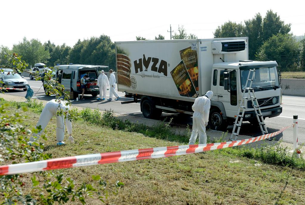 Investigators search  traces at  a  truck that  stands on the shoulder of the highway A4 near Parndorf south of Vienna, Austria, Thursday, Aug 27, 2015. At least 20 migrants were found dead in the truck parked on the Austrian highway leading from the Hungarian border, police said. (APA/ROLAND SCHLAGER)