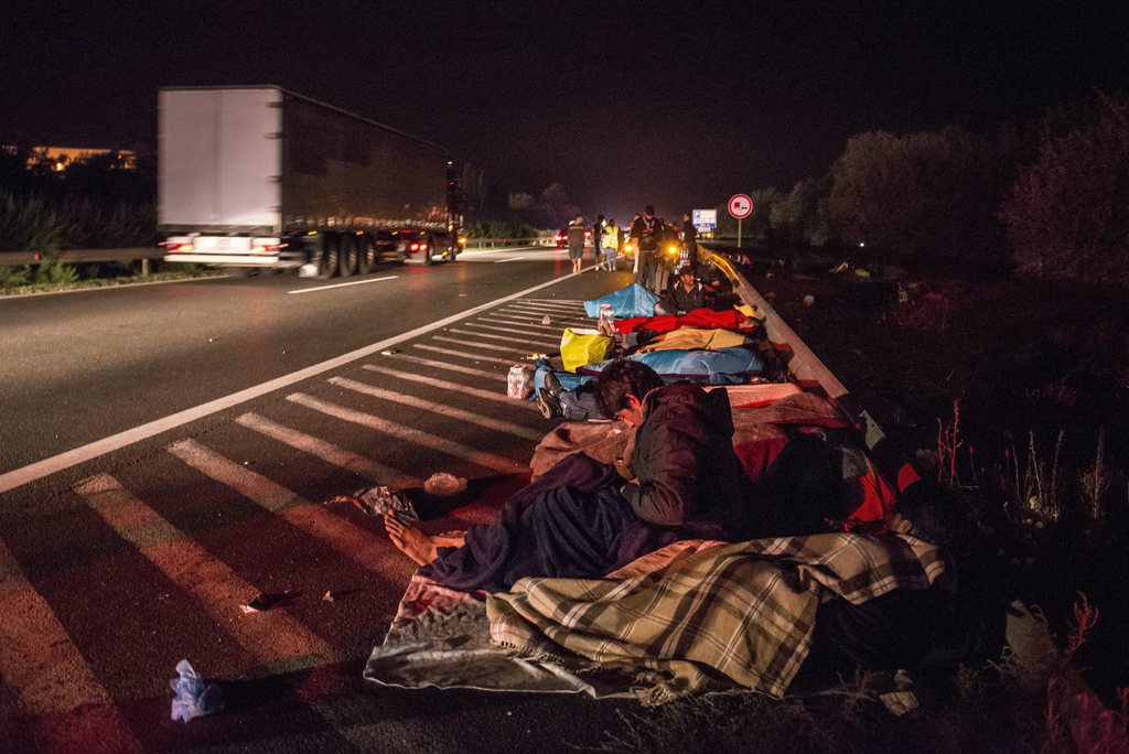 epa04914316 Migrants rest on the side of M1 motorway in Zsambek, 28 kms west of Budapest, Hungary, early 05 September 2015, after some 1,200 migrants marched from Keleti Railway Station in Budapest to this village. Later they boarded buses provided by the Hungarian government to carry them to the Hungarian-Austrian border.  EPA/Boglarka Bognar HUNGARY OUT