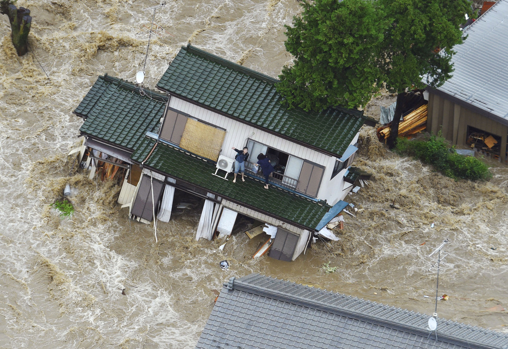 A person inside a house waves to a helicopter as the house is submerged in water flooded from a river in Joso, Ibaraki prefecture, northeast of Tokyo Thursday, Sept. 10, 2015. Heavy rain is pummeling Japan for a second straight day, overflowing rivers and causing landslides and localized flooding in the eastern part of the country. (Kyodo News via AP) JAPAN OUT, MANDATORY CREDIT