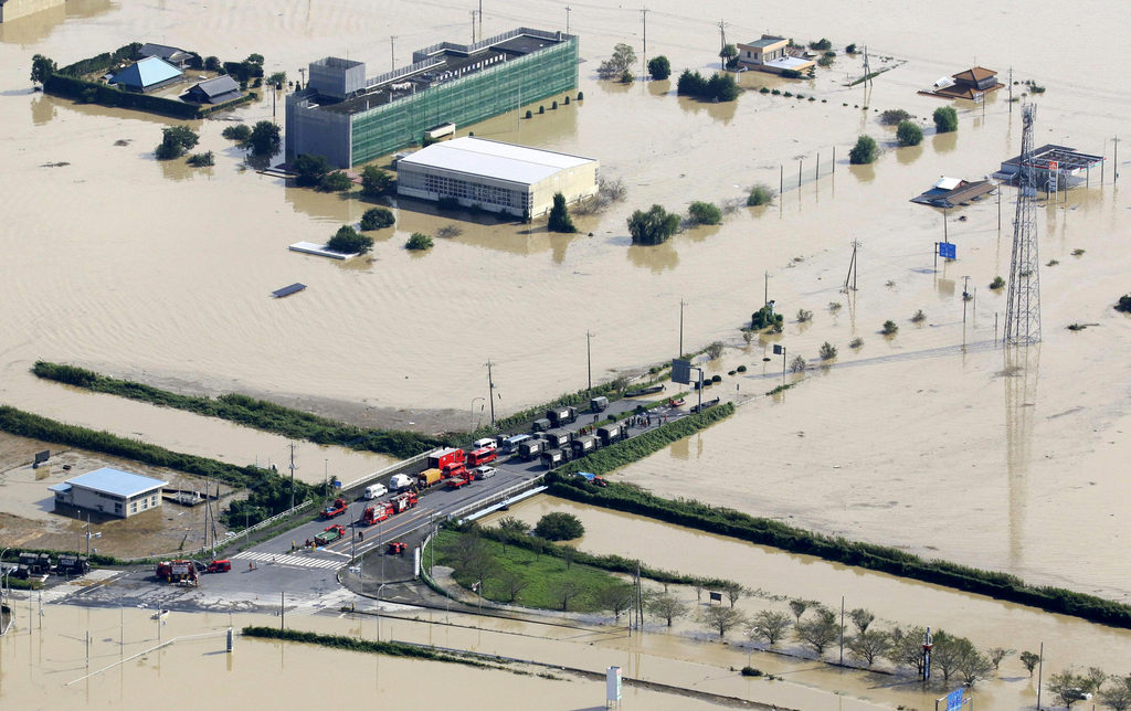 Vehicles of the Ground Self-Defense Force and firefighters are parked at a partially submerged road during a rescue operation in Joso, Ibaraki prefecture, northeast of Tokyo, Friday, Sept. 11, 2015. Rescue workers searched through the flooded city on Friday, hunting for missing people a day after raging floodwaters broke through an embankment and washed away houses and forced dozens of people to rooftops. In Joso city, dozens of residents were airlifted by military helicopters after waiting overnight. (Masanori Takei/Kyodo News via AP) JAPAN OUT, CREDIT MANDATORY