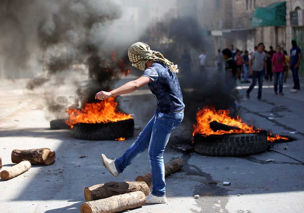 epa04936912 A Palestinian stone thrower during clashes in the West Bank city of Hebron, 18 September 2015. Clashes broke out at several sites in the West Bank in protest against the visit of Israeli Jews to Al Aqsa compound, Islam's third holiest site, in the old city of Jerusalem. Israeli Jews are visiting the Al-Aqsa mosque compound, also called the Temple Mount, for celebrations the Jewish New Year holiday.  EPA/ABED AL HASLHAMOUN