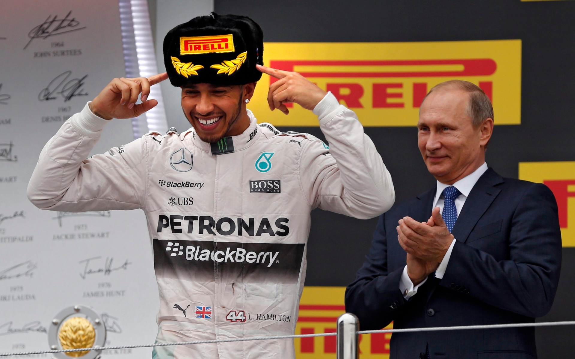 epa04973455 British Formula One driver Lewis Hamilton (L) of Mercedes AMG GP celebrates on the podium as Russian President Vlaimir Putin (R) applauds after winning the 2015 Formula One Grand Prix of Russia at the Sochi Autodrom circuit, in Sochi, Russia, 11 October 2015.  EPA/YURI KOCHETKOV RUSSIA FORMULA ONE GRAND PRIX