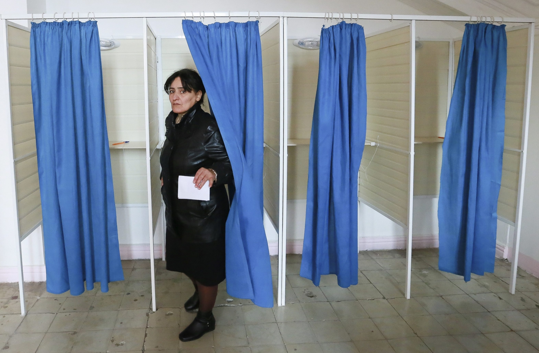 A woman leaves a voting cabin to cast her ballot at a polling station during a parliamentary elections in Baku, Azerbaijan, Sunday, Nov. 1, 2015. Azerbaijani citizens are going to the polls to elect the 125 members of parliament. Voters in the oil-rich Caspian Sea nation of Azerbaijan are casting ballots in a parliamentary election expected to secure the ruling partys dominance. (AP Photo/Aziz Karimov)