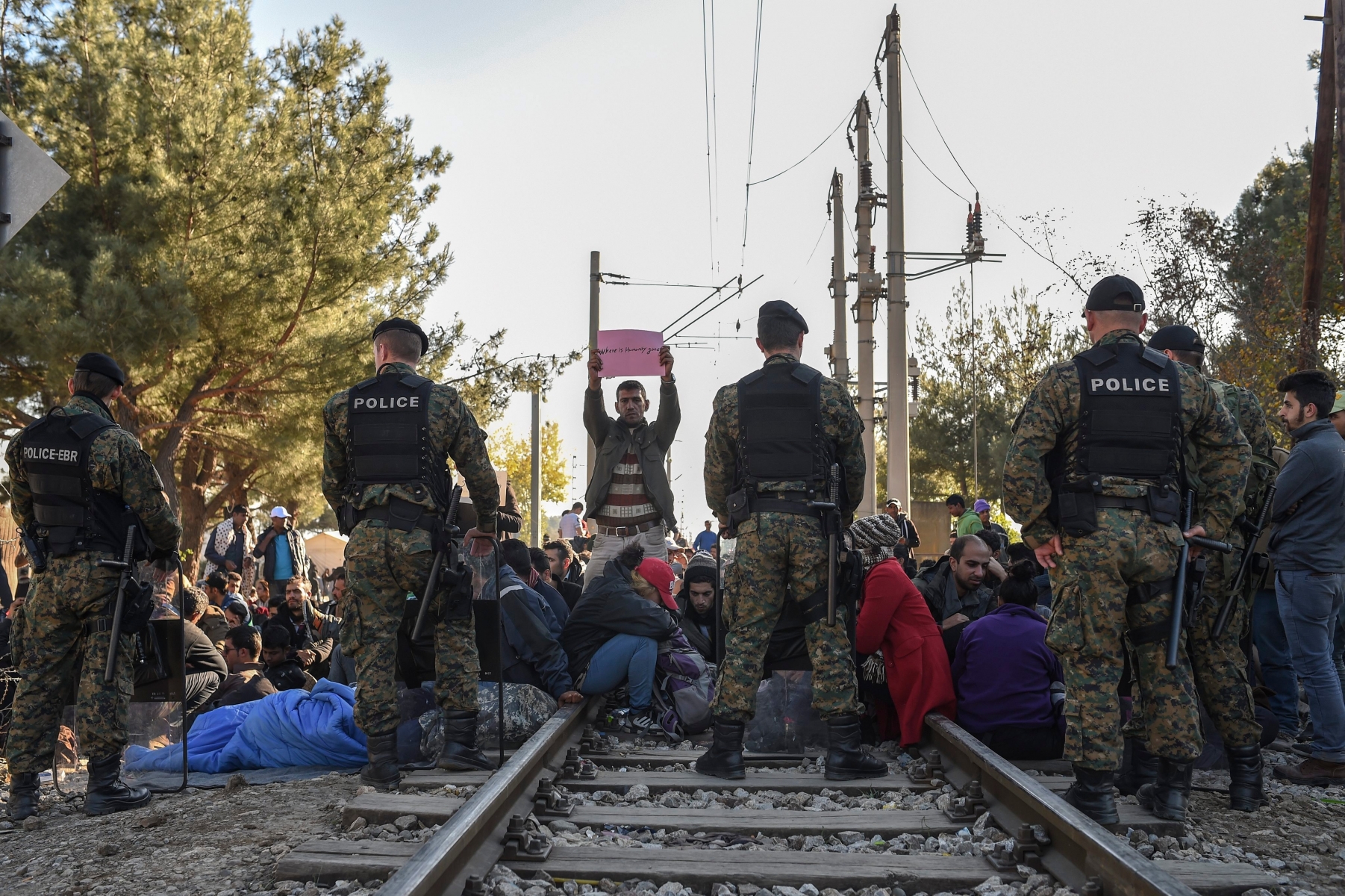 epa05032649 A group of migrants from Iran, Pakistan and Morocco block the border line between Greece and Macedonia as they protest after Macedonia has started granting passage only to refugees from Syria, Iraq and Afghanistan, near Gevegelija, The Former Yugoslav Republic of Macedonia, 19 November 2015. Macedonia, Serbia and Croatia have started restricting access to migrants on the Balkan route to Syrians, Iraqis and Afghans. It is a part of a joint effort to reduce the number of asylum seekers streaming into the European Union.  EPA/GEORGI LICOVSKI FYROM MIGRATION REFUGEES RESTRICTION