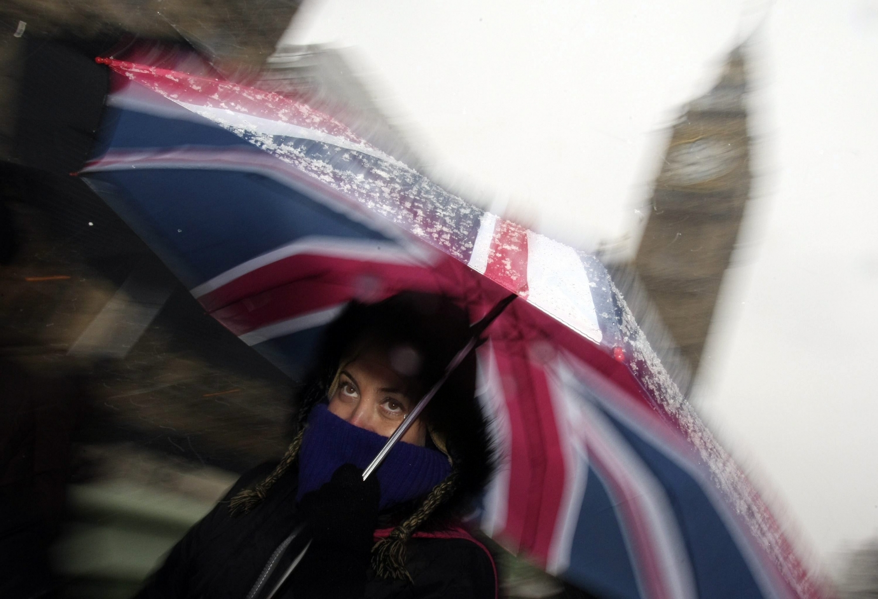 A woman shelters under a Union flag umbrella near the Houses of Parliament, during heavy snow in London, Wednesday, Jan. 6, 2010. Airports and highways were shut, hundreds of schools had to close, and even filming of the venerable television soap opera "Coronation Street" was disrupted as the worst snow and icy weather in years swept Britain. (KEYSTONE/AP Photo/Alastair Grant) Britain Weather