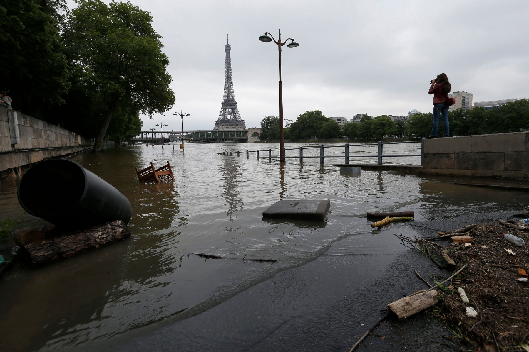 A woman takes photos of the flooded banks of the Seine river in Paris, France Saturday June 4, 2016. The level of the Seine started to drop after peaking earlier in the morning. Both the Louvre and Orsay museums were closed as officials said the Seine had been at its highest level in nearly 35 years. (AP Photo/Francois Mori) France Floods