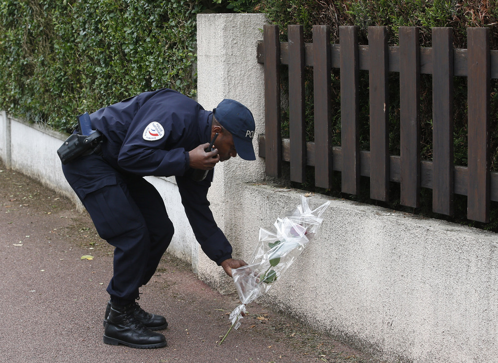Un policier dépose un bouquet de fleurs devant le domicile de son collègue poignardé chez lui à Magnanville, à l'ouest de Paris.
