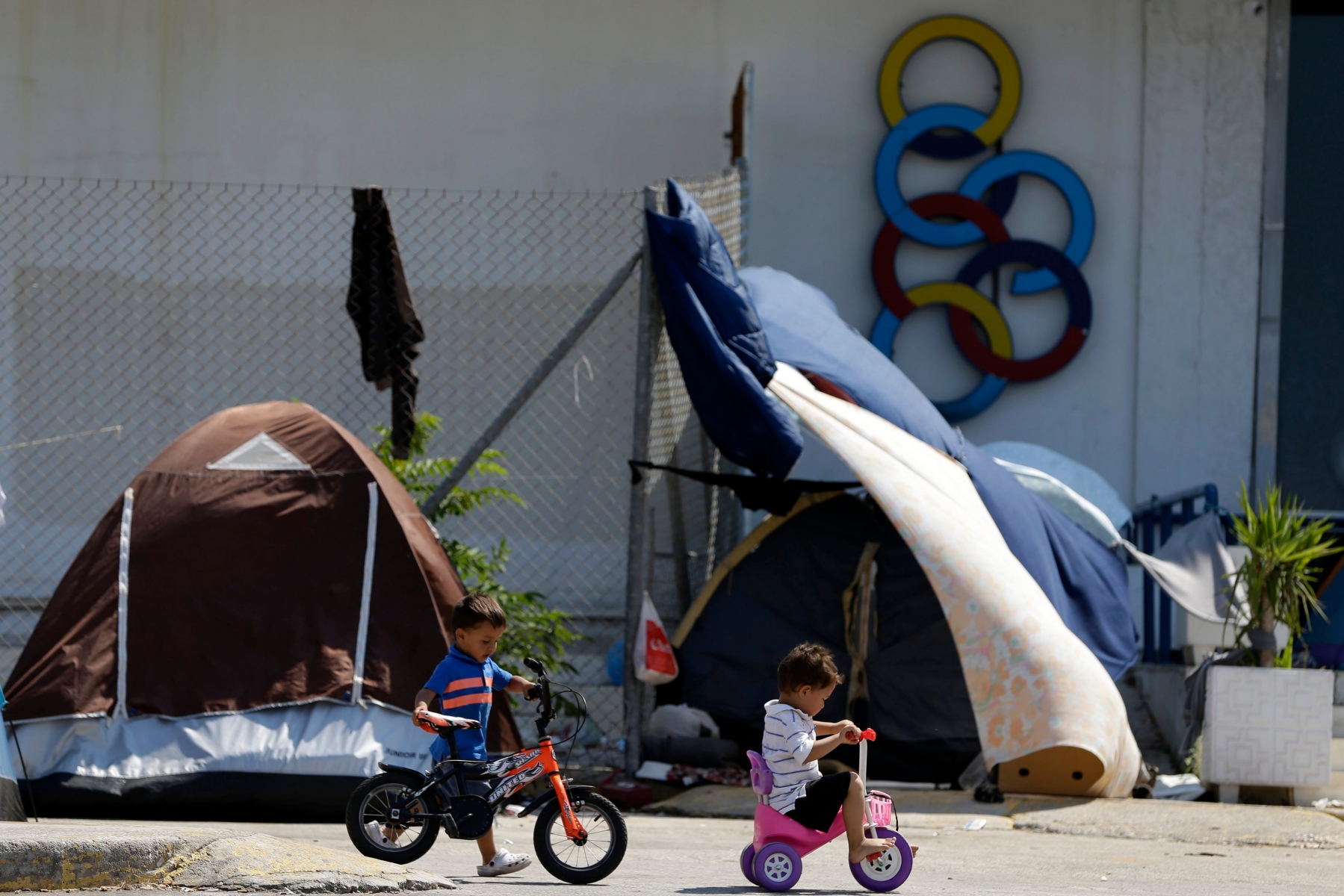Children play next to a logo of Olympic Air at the old international airport, which is used as a shelter for over 2,800 refugees and migrants, in southern Athens, on Thursday, Aug. 4, 2016. Daily arrivals by migrants and refugees at Greek islands near the Turkish coast have remained low since the July 15 coup attempt, but about 57,000 people remain stranded in Greece, most in army-built camps on the mainland. (AP Photo/Thanassis Stavrakis) Greece Migrants