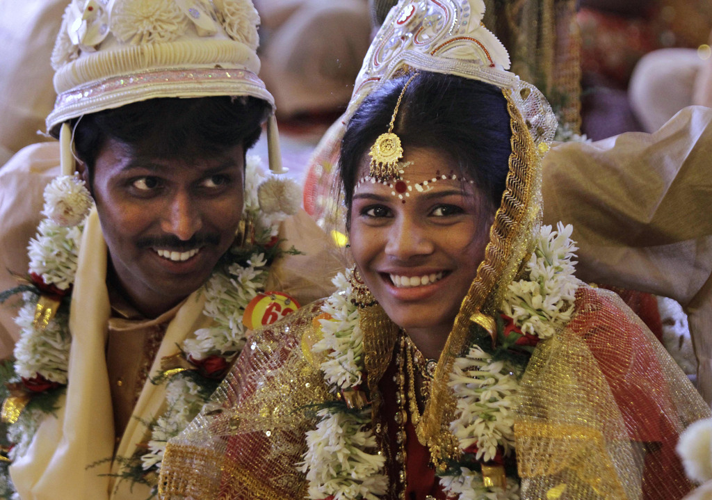 A newly married couple share a light moment during a mass wedding ceremony in Kolkata, India, Sunday, July 1, 2012. The wedding was organized by social organizations primarily to help the families who cannot afford the high ceremony costs as well as the customary dowry and expensive gifts which are still prevalent in many communities. A total of 126 couples tied the knot during the ceremony. (AP Photo/Bikas Das)