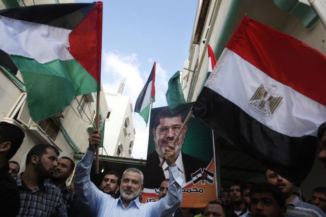 Le président du Hamas, Ismail Haniyeh (centre), a rencontré aujourd'hui le président égyptien Mohamed Morsi (affiche). 