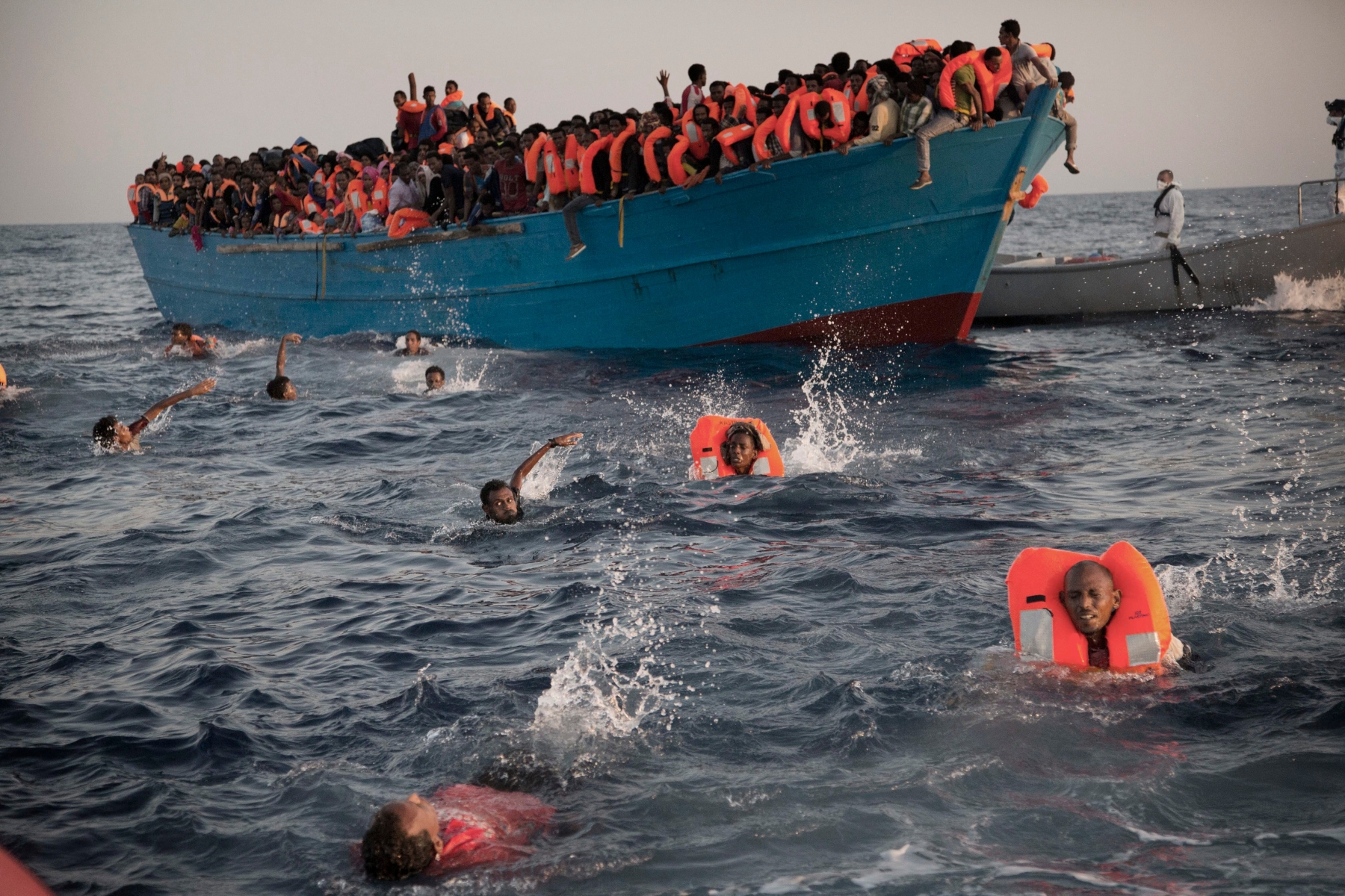 Migrants, most of them from Eritrea, jump into the water from a crowded wooden boat as they are helped by members of an NGO during a rescue operation at the Mediterranean sea, about 13 miles north of Sabratha, Libya, Monday, Aug. 29, 2016. Thousands of migrants and refugees were rescued Monday morning from more than 20 boats by members of Proactiva Open Arms NGO before transferring them to the Italian cost guards and others NGO vessels operating at the zone.(AP Photo/Emilio Morenatti) APTOPIX EU Libya Migrants