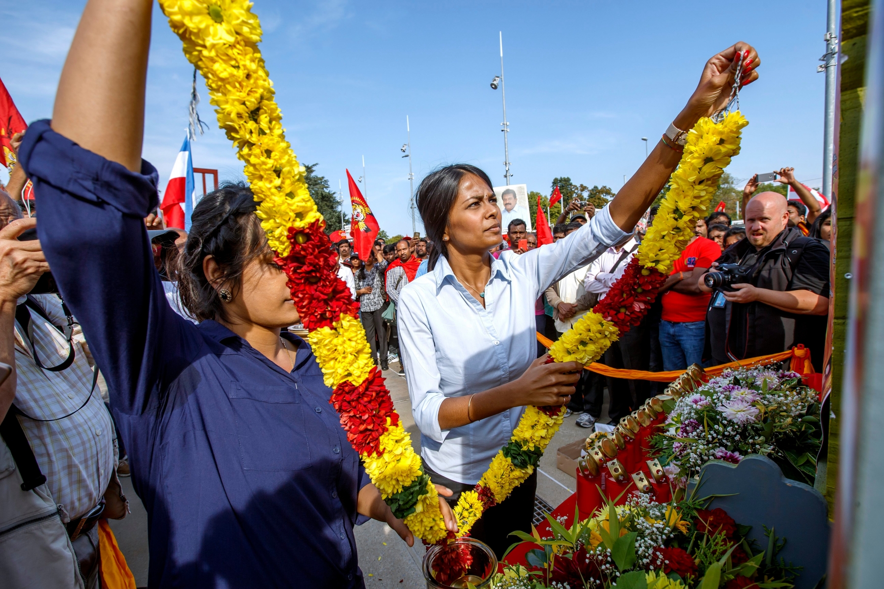 Two women Tamils put flowers in front of the portraits of Tamil victims of the war to pay tribute, during a rally where the participants ask an U.N. inquiry on Sri Lanka, on the Place des Nations in front of the European Headquarters of the United Nations in Geneva, Switzerland, Monday, September 26, 2016. (KEYSTONE/Salvatore Di Nolfi) SWITZERLAND U.N. DEMO TAMIL