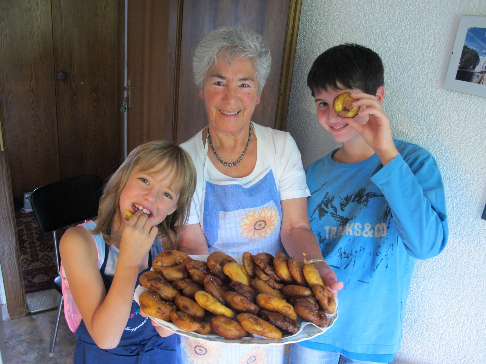 Aline et Benoît entourent Céline, qui présente fièrement la montagne de beignets aux pommes confectionnés ensemble. 
