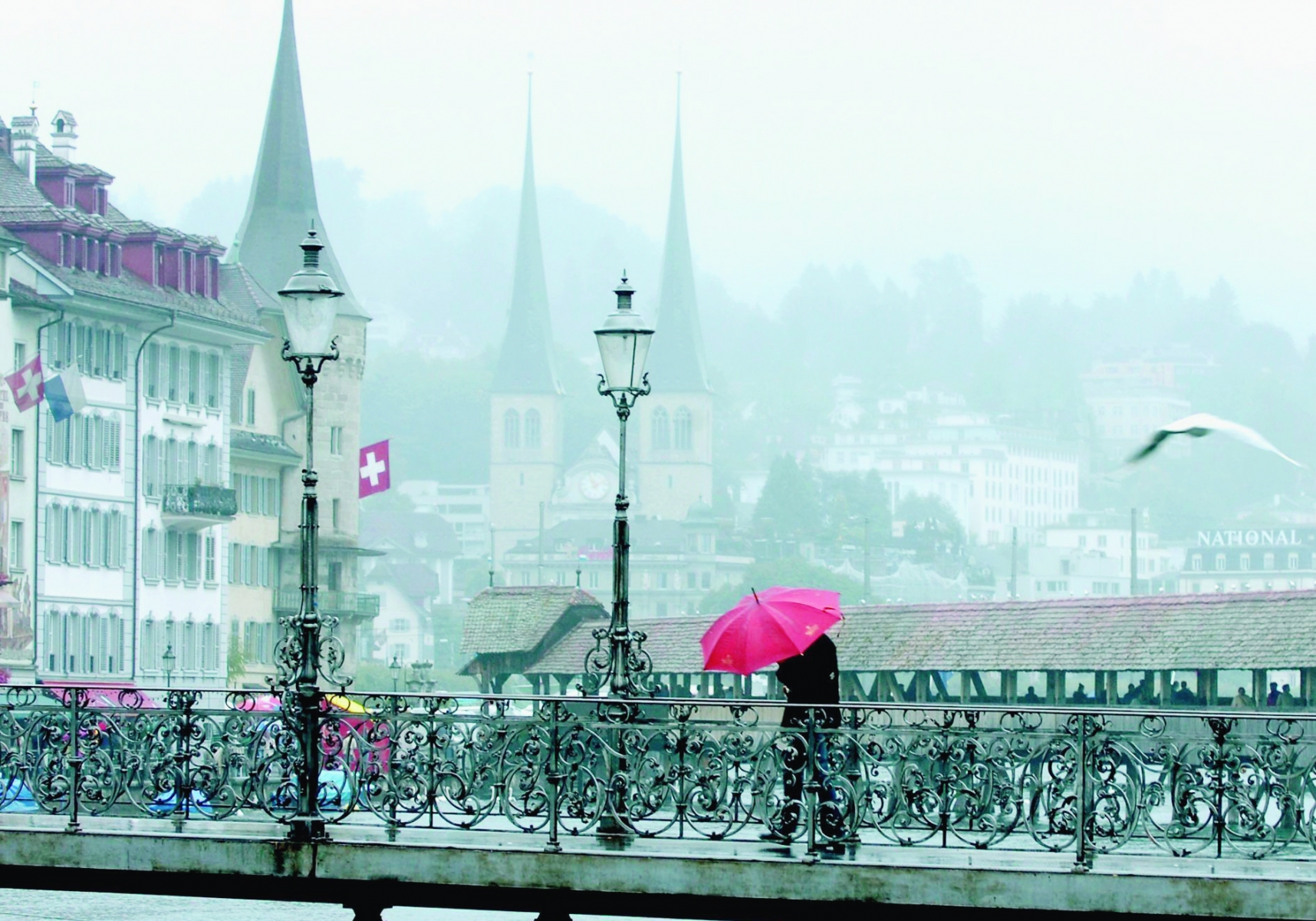 Bei regnerischem nebelverhangenem Wetter vermochten am Mittwoch, 3. August 2005 in Luzern nur Schirme und Fahnen etwas Farbe auf dem Rathaussteg bringen. (KEYSTONE/Sigi Tischler) SCHWEIZ WETTER LUZERN
