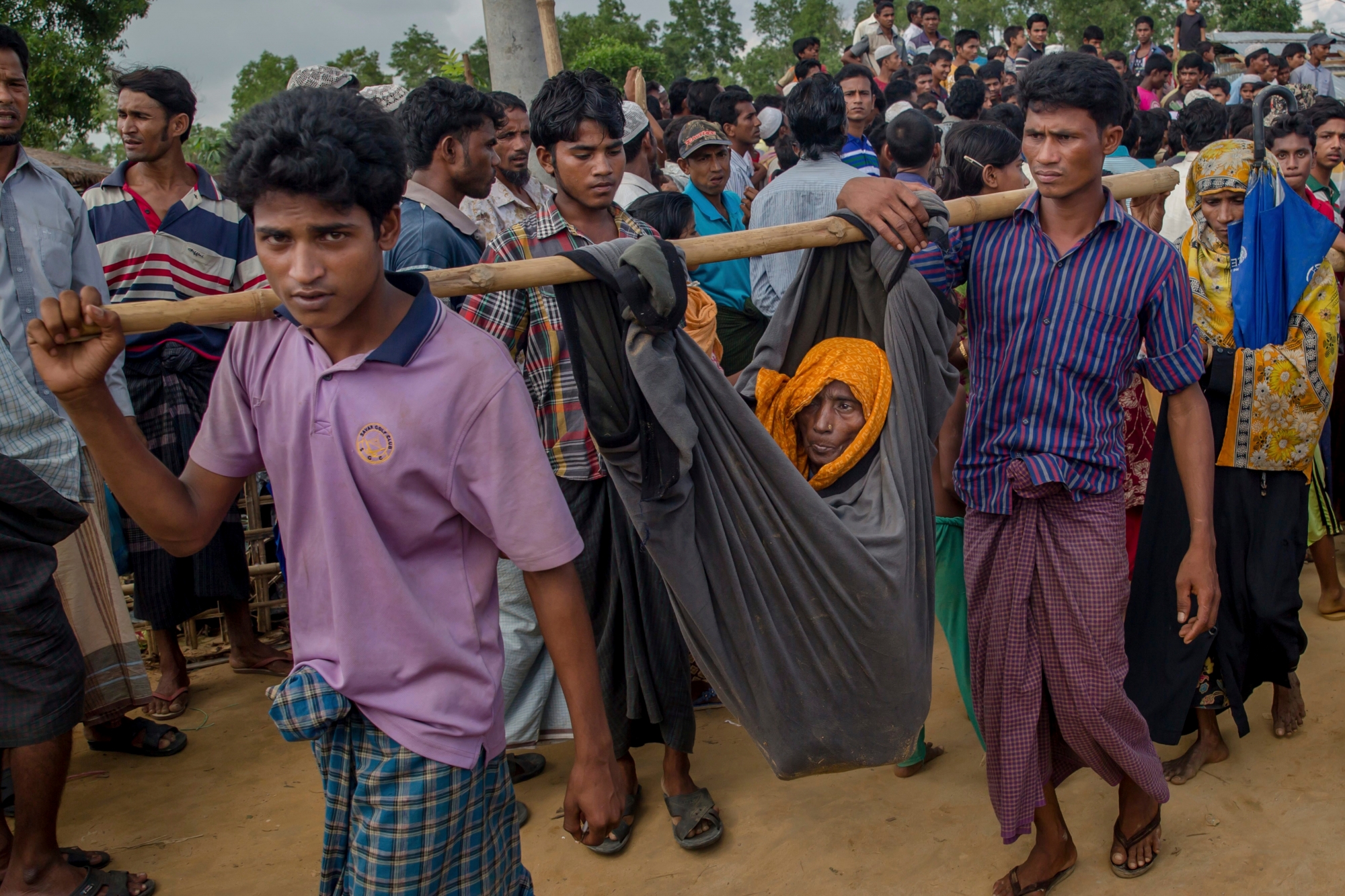Rohingya Muslim men, who crossed over from Myanmar into Bangladesh, carry their mother in a cloth tied to bamboo stick at Kutupalong refugee camp, Bangladesh, Monday, Oct. 23, 2017. U.N. humanitarian officials, high-level government envoys and advocacy group leaders on Monday opened a one-day conference aimed at drumming up funds to help ethnic Rohingya refugees in Bangladesh, as the influx from Myanmar has topped 600,000 since late August. (AP Photo/Dar Yasin) Bangladesh Myanmar Attacks