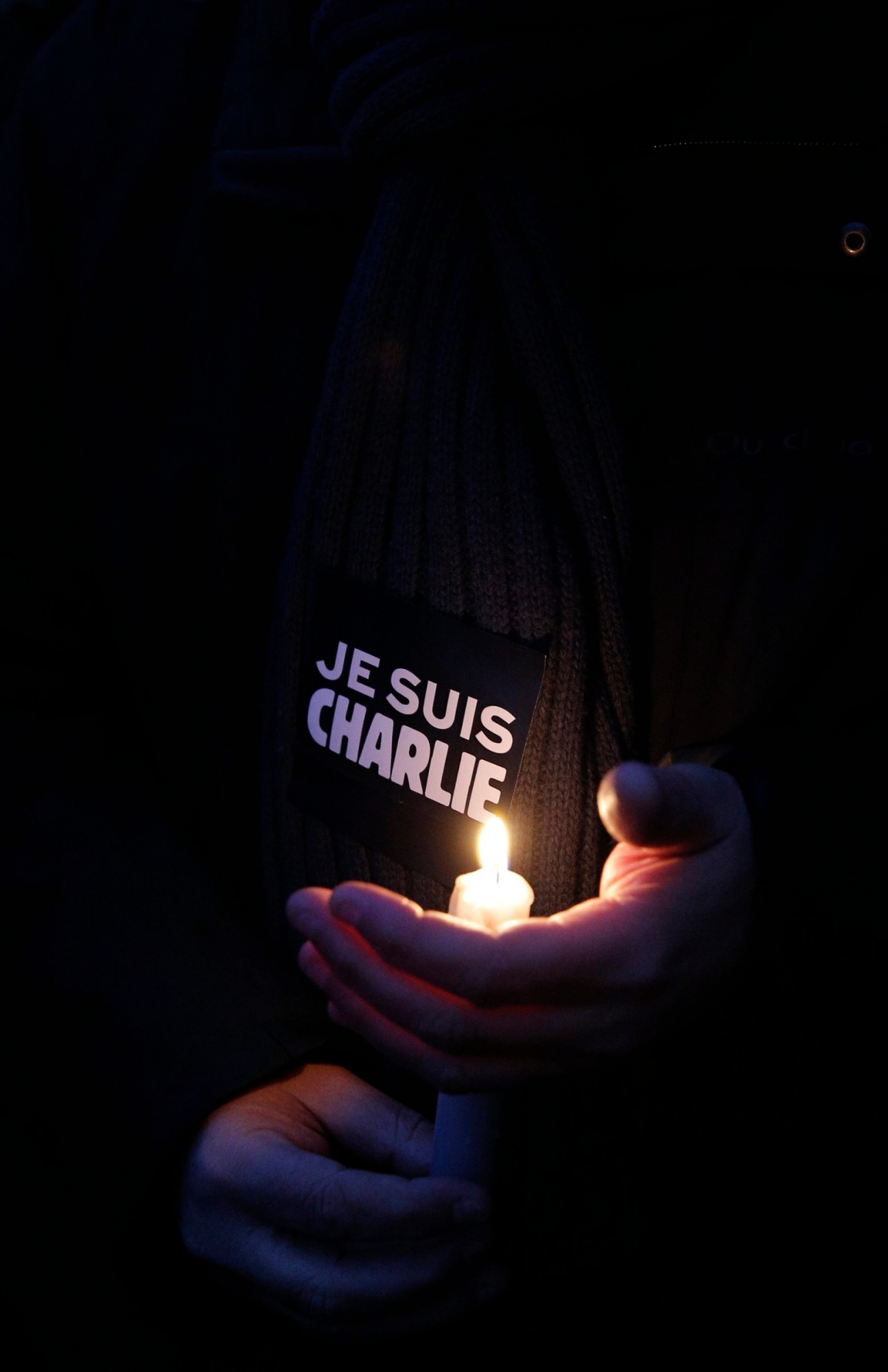 A man holds a candle and a sticker reading " I am Charlie", during a demonstration in Paris, Wednesday, Jan. 7, 2015. Three masked gunmen shouting "Allahu akbar!" stormed the Paris offices of a satirical newspaper, Charlie Hebdo, Wednesday, killing 12 people, including its editor, before escaping in a car. It was France's deadliest postwar terrorist attack. (AP Photo/Christophe Ena) APTOPIX France Newspaper Attack