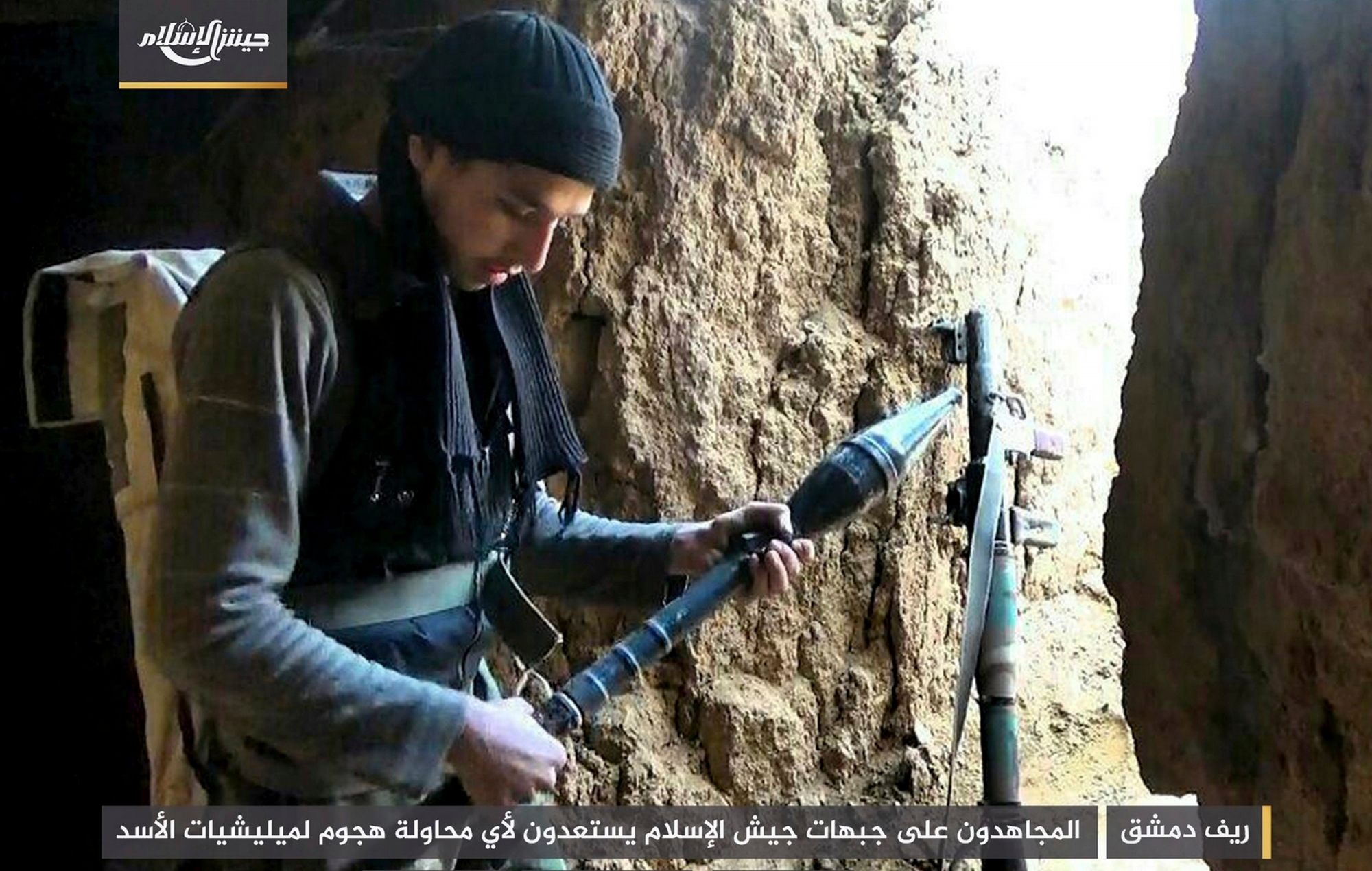 This photo posted Tuesday, Feb 20, 2018, by the Syrian insurgent group Army of Islam, shows a fighter with the Army of Islam rebel group, as he prepares a rocket propelled grenade in the suburbs of the Syrian capital Damascus. Many of the fighters entrenched in the Damascus suburb of eastern Ghouta are originally from the area and move around using an elaborate network of underground tunnels, giving them an advantage against President Bashar Assad's forces and their allies. Arabic reads, "Damascus Suburbs: Holy warriors on the fronts of the Army of Islam getting ready for any attempt by Assad's military to launch an attack." (Army of Islam, via AP) Syria Ghouta Fighters