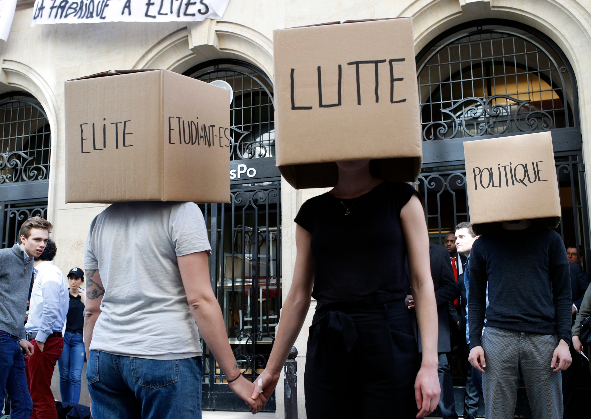 Students wearing boxes reading "Elite, Students, Struggle, Politics," perform in front of a blocked entry at the Institute of Political Studies(IEP) or Sciences Po, in Paris, France, Wednesday, April 18, 2018. French students intensified blockades of universities over the government's reform. (AP Photo/Francois Mori) France Students Strikes
