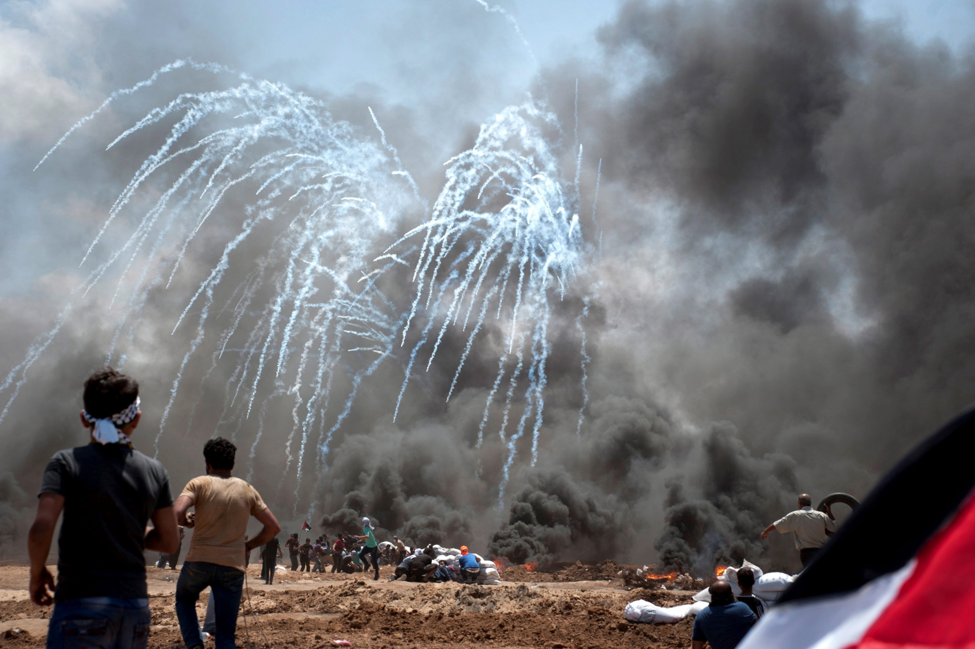 epa06735604 Israeli army throws tear gas during Palestinian demonstrators during a protest against the US Embassy move to Jerusalem and ahead of the 70th anniversary of Nakba, at the Gaza-Israeli border, in Abu Safia, Gaza Strip, 14 May 2018. Palestinians are marking the Nakba Day, or the day of the disaster, when more than 700 thousand Palestinians were forcefully expelled from their villages during the war that led to the creation of the state of Israel on 15 May 1948. Protesters call for the right of Palestinians to return to their homeland.  EPA/LUCA PIERGIOVANNI MIDEAST PALESTINIANS ISRAEL GAZA PROTEST