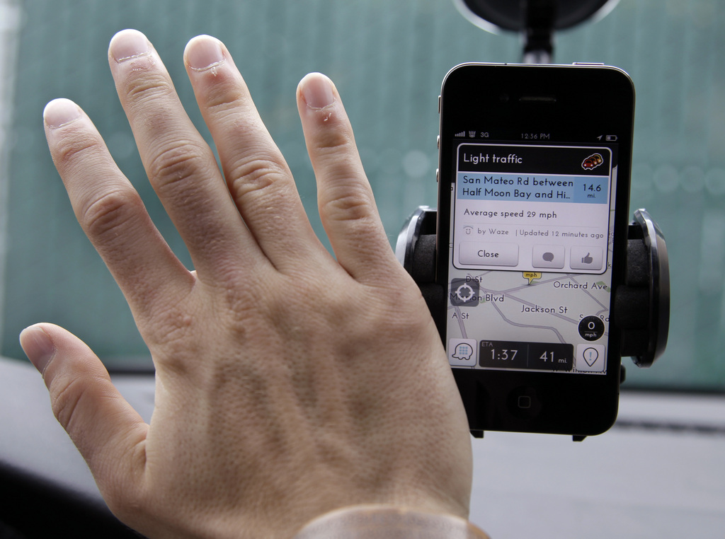 In this March 15, 2012 photo, Ben Gleitzman waves his hand over a traffic and navigation app called Waze on his Apple iPhone in a Menlo Park, Calif., parking lot during a demonstration showing traffic conditions on the display. Thousands of enthusiasts traveling the world using little more than GPS-equipped smartphones are helping Waze and other services to build in-depth maps of cities and countries around the world. Consumers, companies and even disaster relief organizations have come to rely on such ?crowdsourced? maps and the ability to update them almost instantaneously. (AP Photo/Paul Sakuma)
