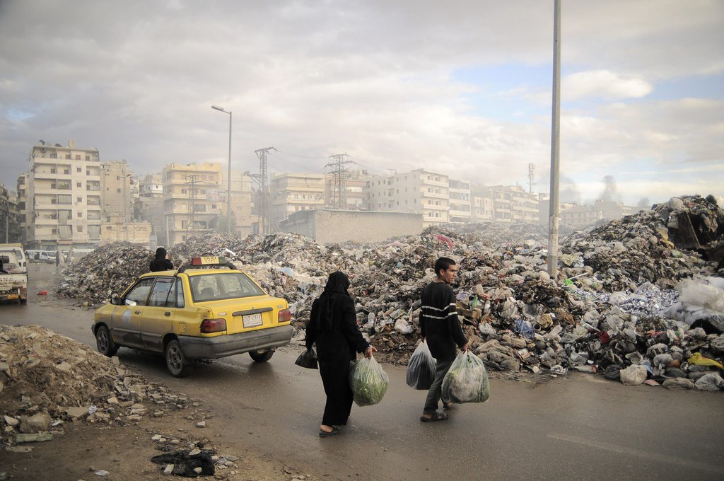 In this Saturday, Nov. 10, 2012 photo, Syrians carry their rubbish to a mountain of garbage in a roundabout in Aleppo, Syria. Due the heavy fighting and shelling, the garbage collection system collapsed weeks ago. (AP Photo/M?nica G. Prieto)