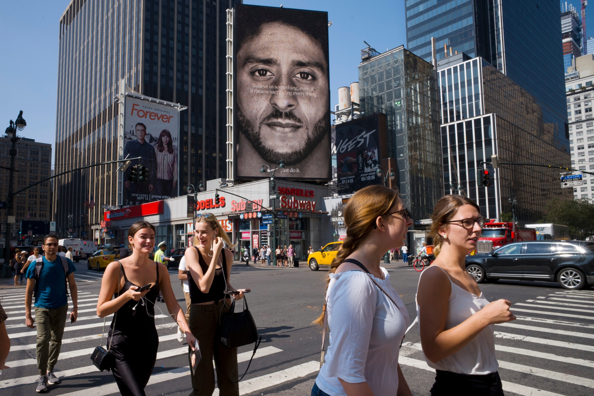 People walk by a Nike advertisement featuring Colin Kaepernick on display, Thursday, Sept. 6, 2018, in New York. Nike this week unveiled the deal with the former San Francisco 49ers quarterback, who's known for starting protests among NFL players over police brutality and racial inequality. (AP Photo/Mark Lennihan) APTOPIX Trump Nike