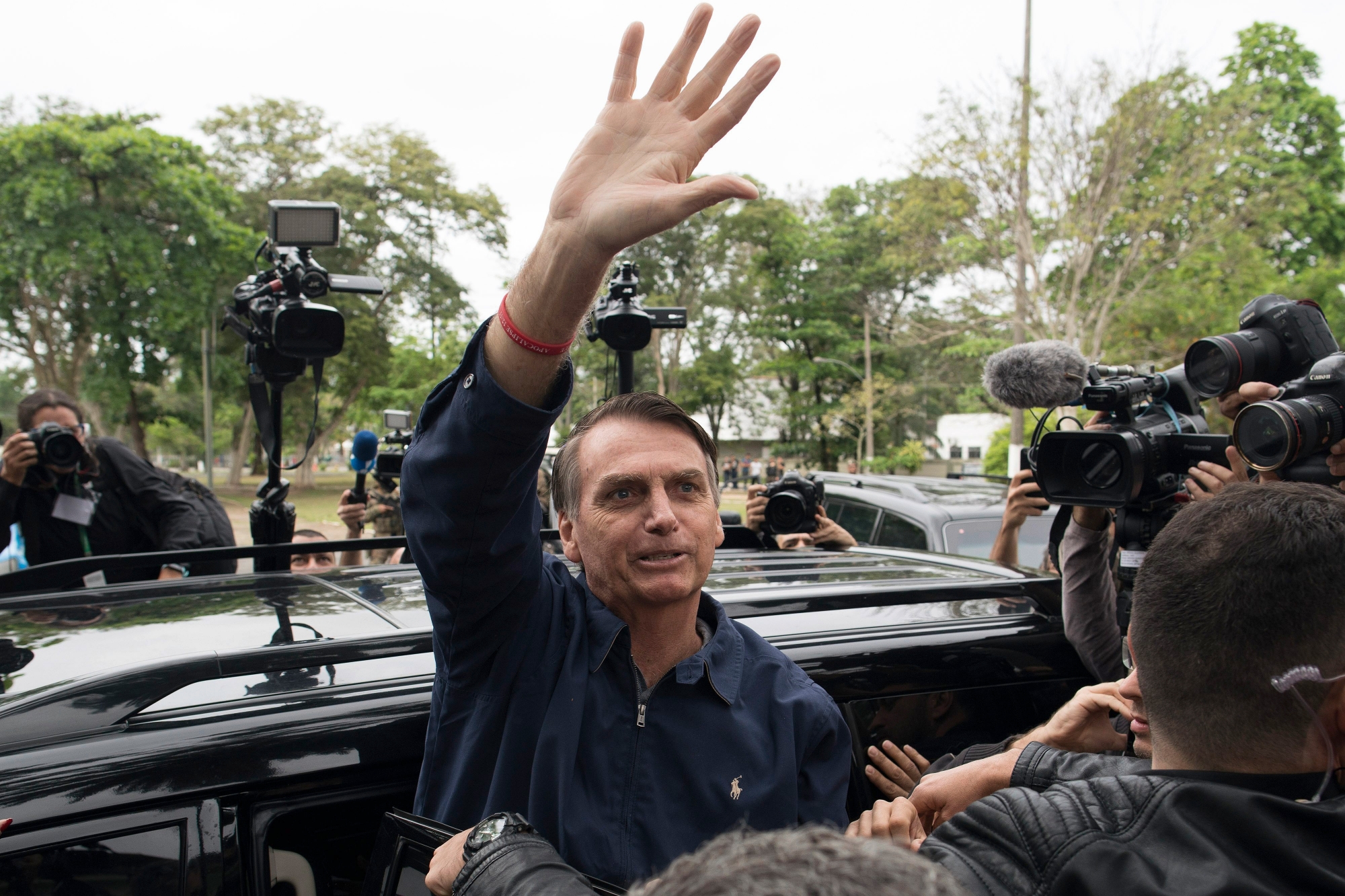 Presidential frontrunner Jair Bolsonaro, of the Social Liberal Party, waves to supporters after voting at a polling station in Rio de Janeiro, Brazil, Sunday, Oct. 7, 2018. Brazilians choose among 13 candidates for president Sunday in one of the most unpredictable and divisive elections in decades. If no one gets a majority in the first round, the top two candidates will compete in a runoff. (AP Photo/Leo Correa) Brazil Elections