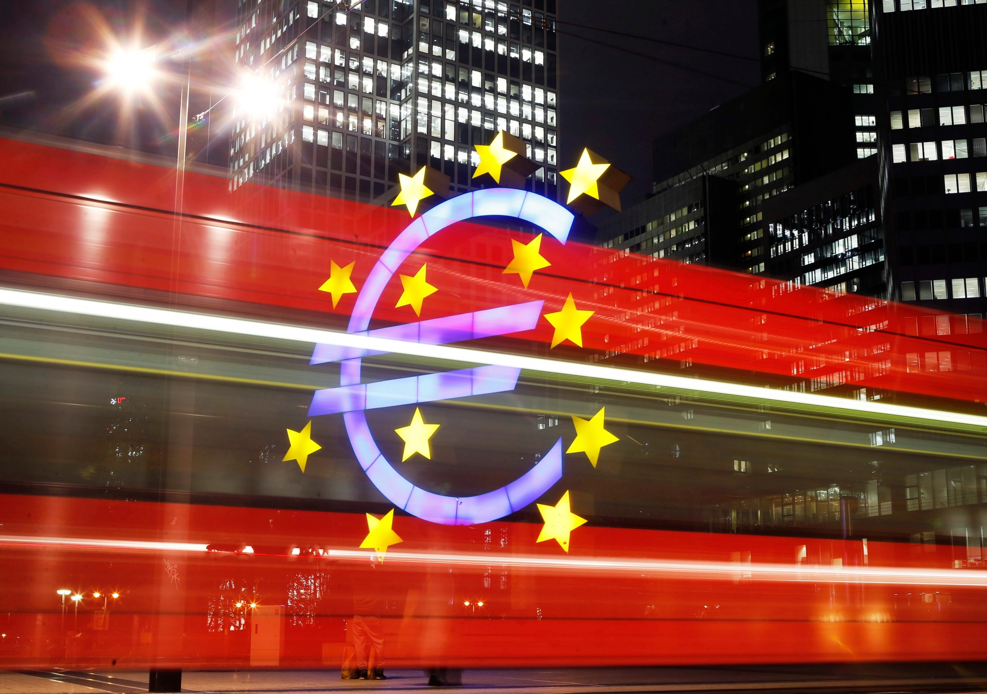 FILE - In this Monday, Oct. 27, 2014 file photo taken with long time exposure, shows a tram passing by the Euro sculpture in front of the European Central Bank in Frankfurt, Germany. Europe's experiment with sharing a currency is turning 20 in a few days. The euro is credited with increasing trade between members. But countries have struggled to adjust to trouble after giving up two big safety valves: the ability to let their currency's exchange rate fall to boost exports, and to adjust own interest rates to stimulate business activity. (AP Photo/Michael Probst, File) EU The Euro at 20