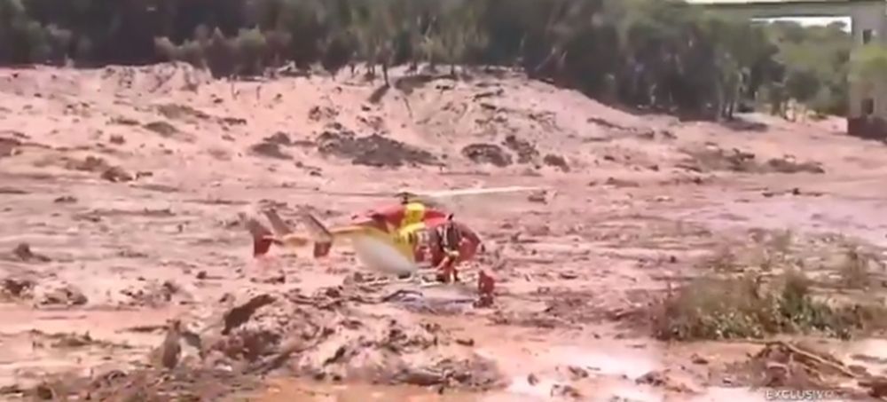 Cet hélicoptère s'approche de deux personnes enlisées dans la boue jusqu'à la taille.