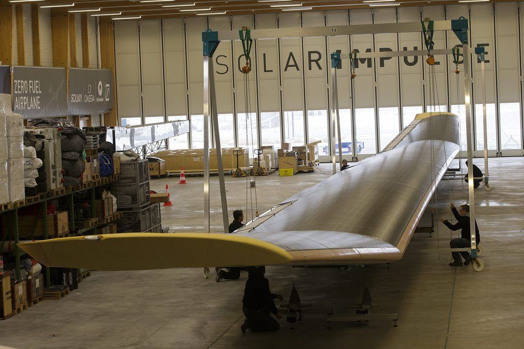 Des techniciens de Solar Impulse lui enlèvent ses ailes pour le transporter à bord d'un Jumbo jet. 