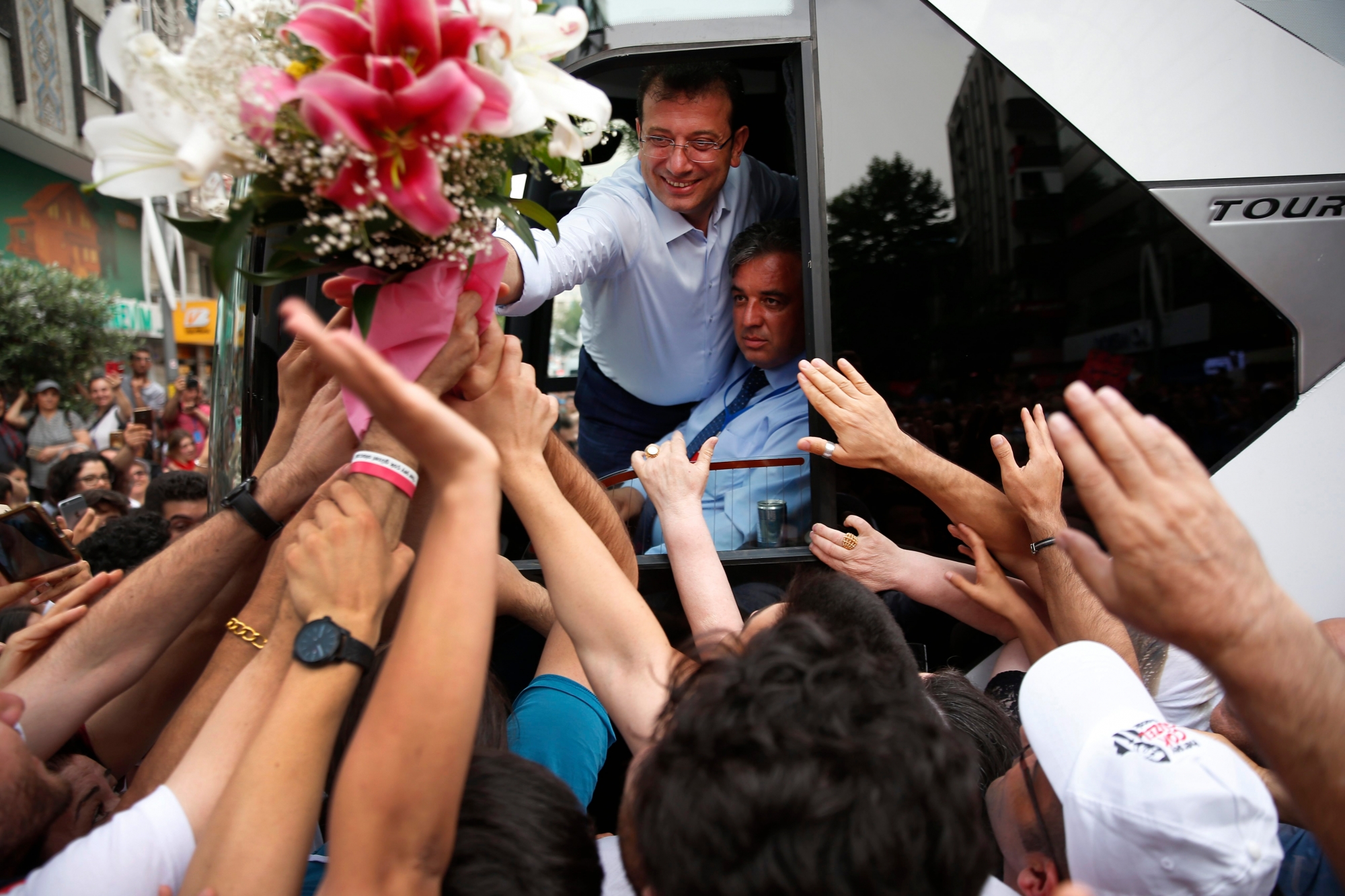 Ekrem Imamoglu, candidate of the secular opposition Republican People's Party, or CHP, reaches out from his campaign bus to supporters after a rally in Istanbul, Wednesday, June 19, 2019, ahead of June 23 re-run of Istanbul elections. The 49-year-old candidate won the March 31 local elections with a slim majority, but after weeks of recounting requested by the ruling party, Turkey's electoral authority annulled the result of the vote, revoked his mandate and ordered the new election. (AP Photo/Lefteris Pitarakis) APTOPIX Turkey Local Elections