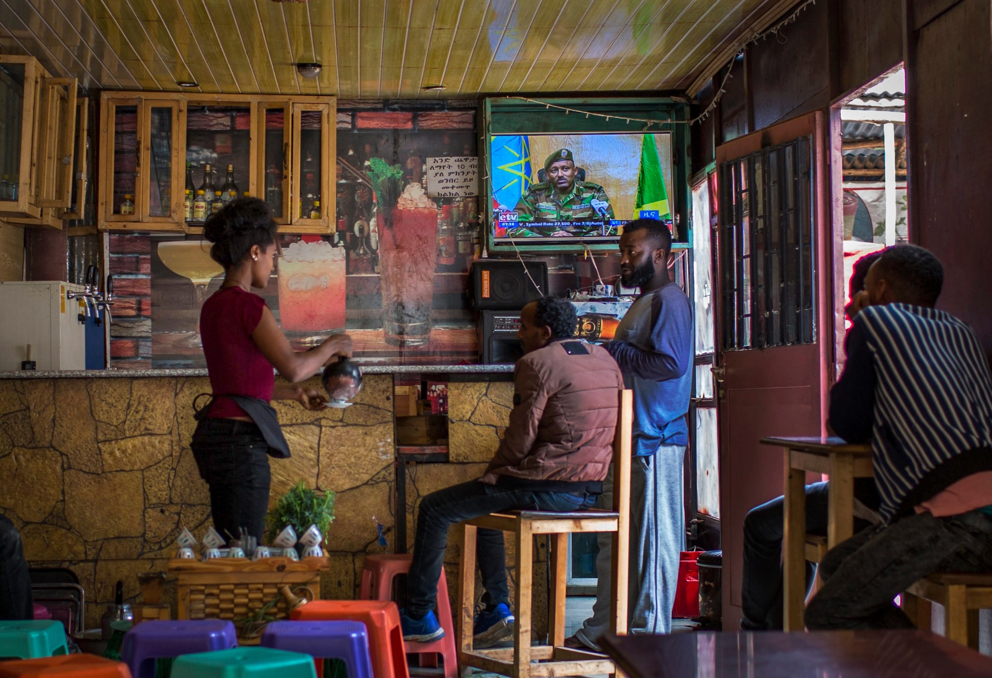 Ethiopians follow the news on television at a cafe in Addis Ababa, Ethiopia Sunday, June 23, 2019. Ethiopia's government foiled a coup attempt in a region north of the capital and the country's military chief was shot dead, the prime minister Abiy Ahmed said Sunday in a TV announcement. (AP Photo/Mulugeta Ayene) Ethiopia Unrest