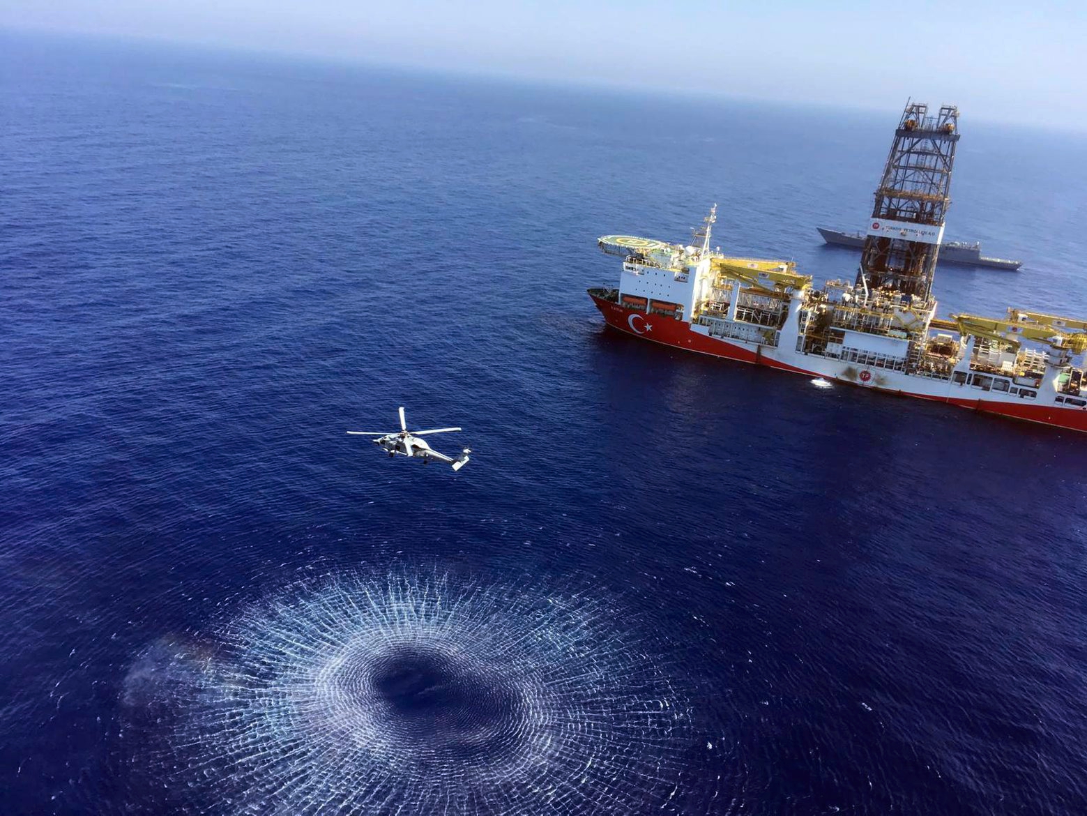 In this Tuesday, July 9, 2019 photo, a helicopter flies near Turkey's drilling ship, 'Fatih' dispatched towards the eastern Mediterranean, near Cyprus. Turkish officials say the drillships Fatih and Yavuz will drill for gas, which has prompted protests from Cyprus.(Turkish Defence Ministry via AP, Pool) Turkey Cyprus Drilling