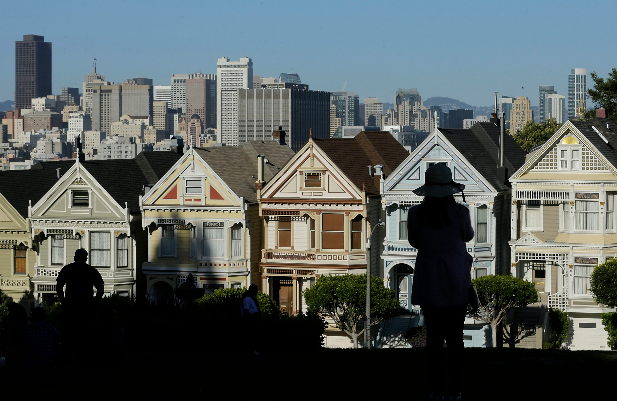 FILE- In this April 15, 2016, file photo a woman looks toward the "Painted Ladies," a row of historical Victorian homes, with the San Francisco skyline at rear at Alamo Square Park in San Francisco. The Trump administration announced new rules Thursday, Aug. 23, 2018, aimed at preventing residents in high-tax states from avoiding a new cap on widely popular state and local tax deductions. (AP Photo/Jeff Chiu, File) TAX OVERHAUL HIGH TAX STATES
