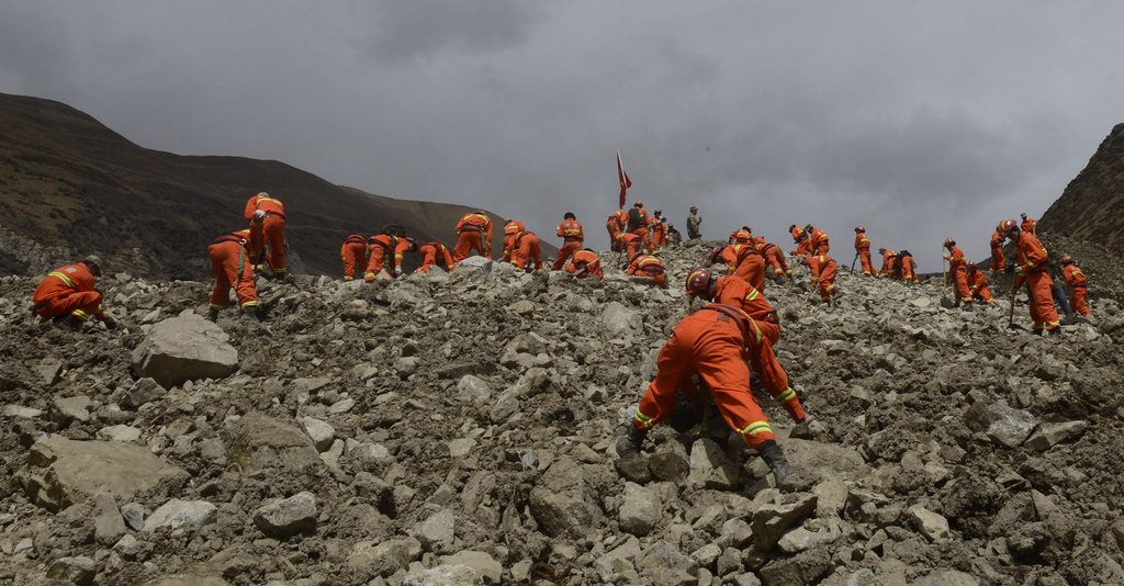 In this March 30, 2013 photo provided by China's Xinhua News Agency, rescue workers conduct search and rescue work at the site where a large-scale landslide hit a mining area in Maizhokunggar County of Lhasa, southwest China's Tibet Autonomous Region. Emergency crews in Tibet slogged through pileups of earth up to 30 meters (100 feet) deep Sunday after a massive mudslide at a gold mine buried 83 workers, and authorities said chances were slim for finding any survivors.  (AP Photo/Xinhua, Purbu Zhaxi)  NO SALES