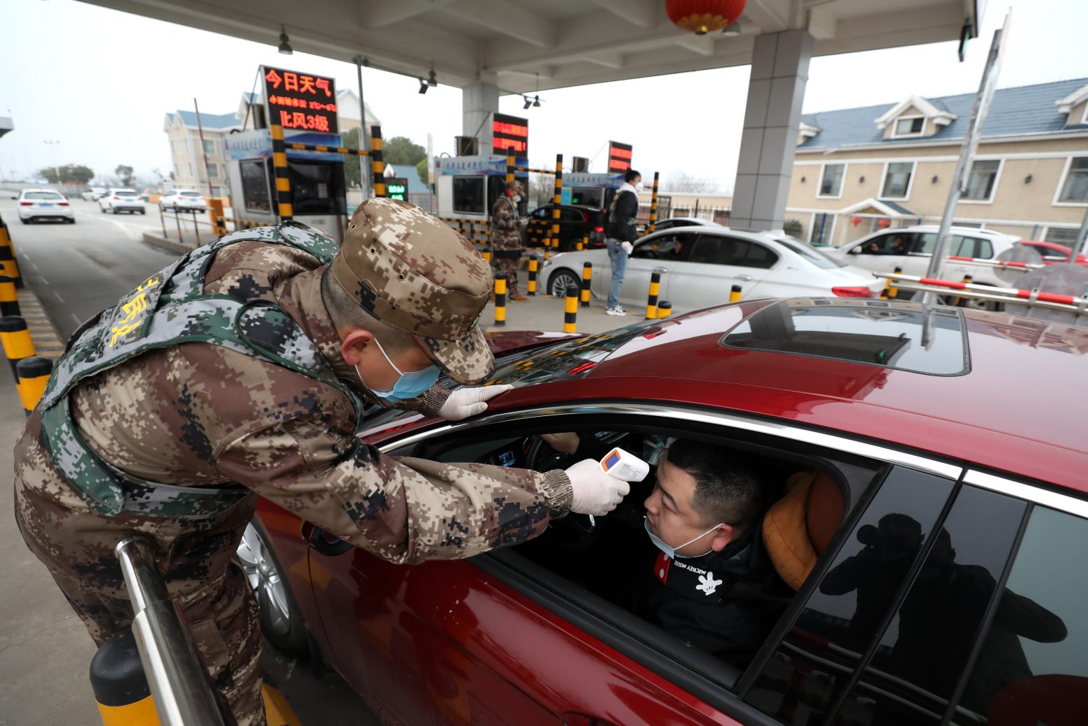 epa08155521 A militia member checks the body temperature of a driver on a vehicle at an expressway toll gate in Wuhan in central China's Hubei province, 23 January 2020, in a bid to contain the spread of the new coronavirus.  EPA/YUAN ZHENG CHINA OUT CHINA WUHAN FEVER CHECK
