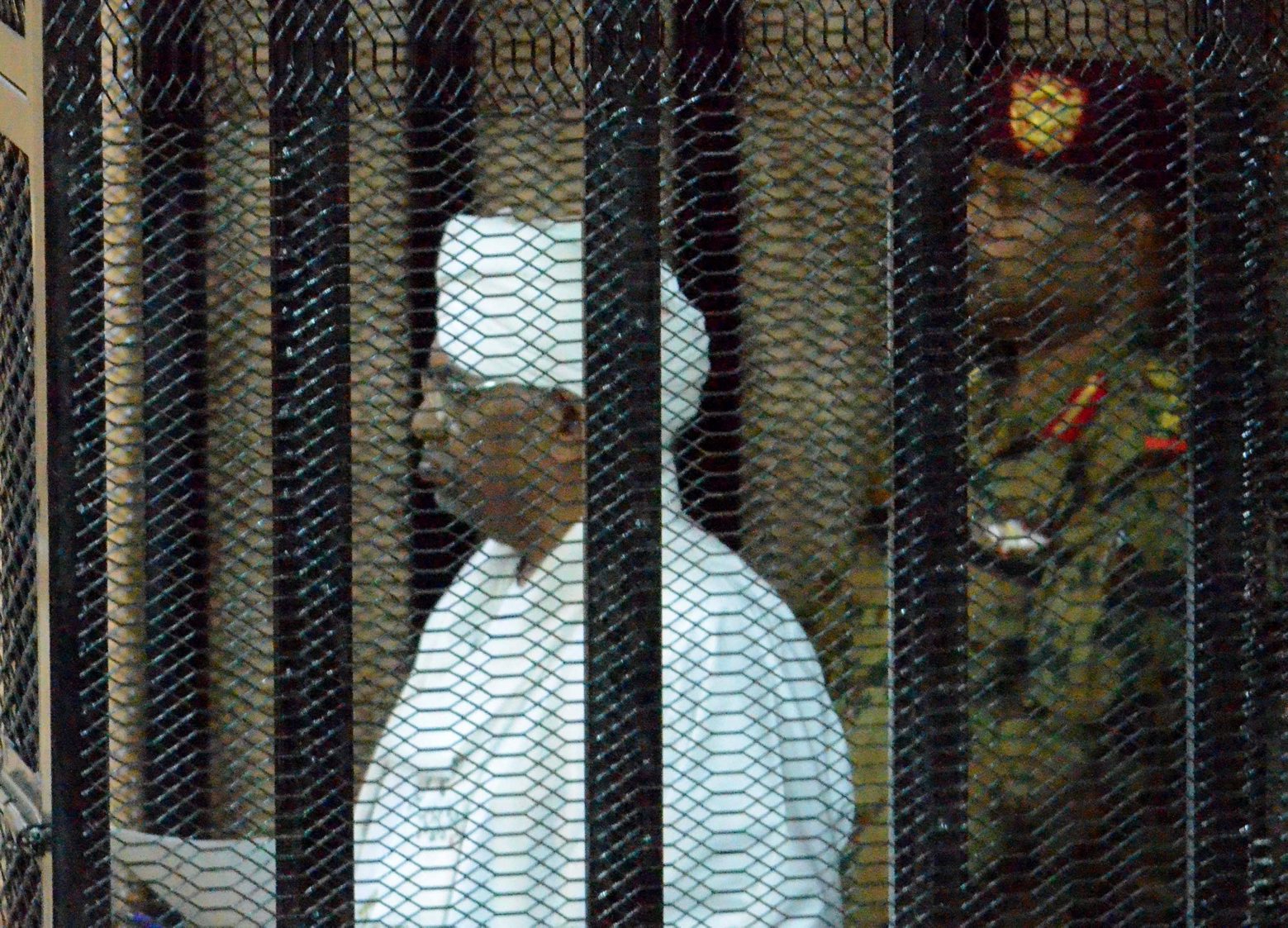 epa07780604 Sudan's ousted president Omar Hassan al-Bashir (L) stands in a cage during his trial at a courtroom in Khartoum, Sudan, 19 August 2019. Al-Bashir was ousted on 11 April after months of protests and some 30 years in power. According to local media reports, al-Bashir returned to court on 19 August to answer for corruption charges. The trial resumed two days after the military council and the opposition signed a power sharing deal, hoping to end months of crisis.  EPA/STRINGER SUDAN FORMER PRESIDENT TRIAL