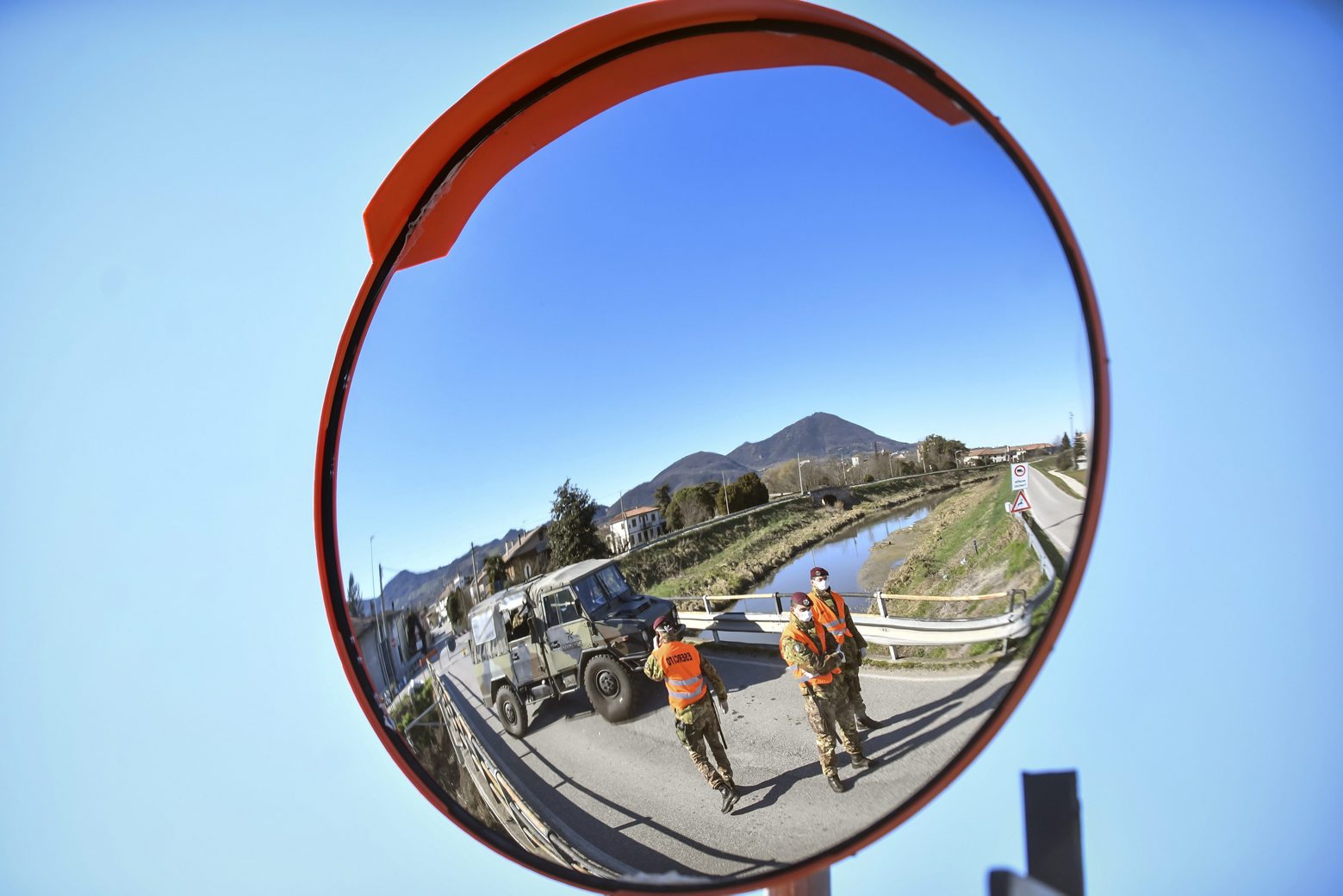 Italian army personnel are reflected in a traffic mirror as they man a road block on the way to the village of Vo'Euganeo, in Italy's northern Veneto region, on Friday, Feb. 28, 2020. Vo'Euganeo is the epicenter of the Veneto cluster of the new virus. (Claudio Fulan/LaPresse via AP) Italy Virus Outbreak