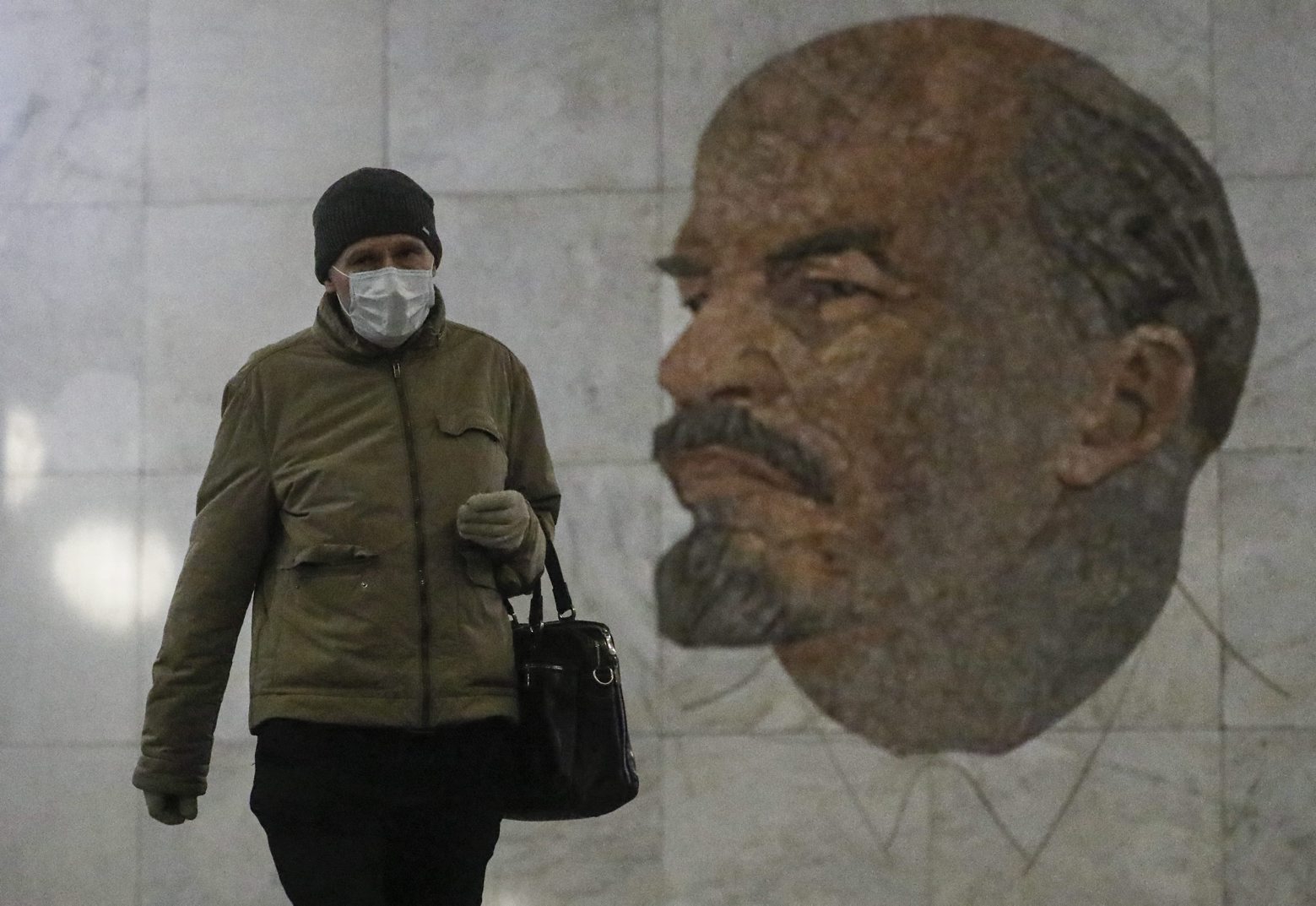 epa08419500 A commuter wearing a face mask and gloves walks in front of a famous mosaic depicting the portrait of Soviet Union founder Vladimir Ilyich Ulyanov (1870-1924) â?? better known by his nom de guerre, 'Lenin' â?? created in 1965 by artist Grigory Opryshko at the Biblioteka Imeni Lenina metro station in Moscow, Russia, 13 May 2020. Last week, Moscow Mayor Sergey Sobyanin announced that work would resume at industrial and construction businesses in Moscow starting on 12 May as part of an economic reactivation plan amid the ongoing pandemic of the COVID-19 disease caused by the SARS-CoV-2 coronavirus. Residents of the Russian capital are now required to wear face masks and gloves when using public transport and inside shops. Other restrictions, such as the closure of public parks and general stay-at-home and social distancing guidances, are set to remain in place until 31 May.  EPA/SERGEI ILNITSKY RUSSIA PANDEMIC CORONAVIRUS COVID19