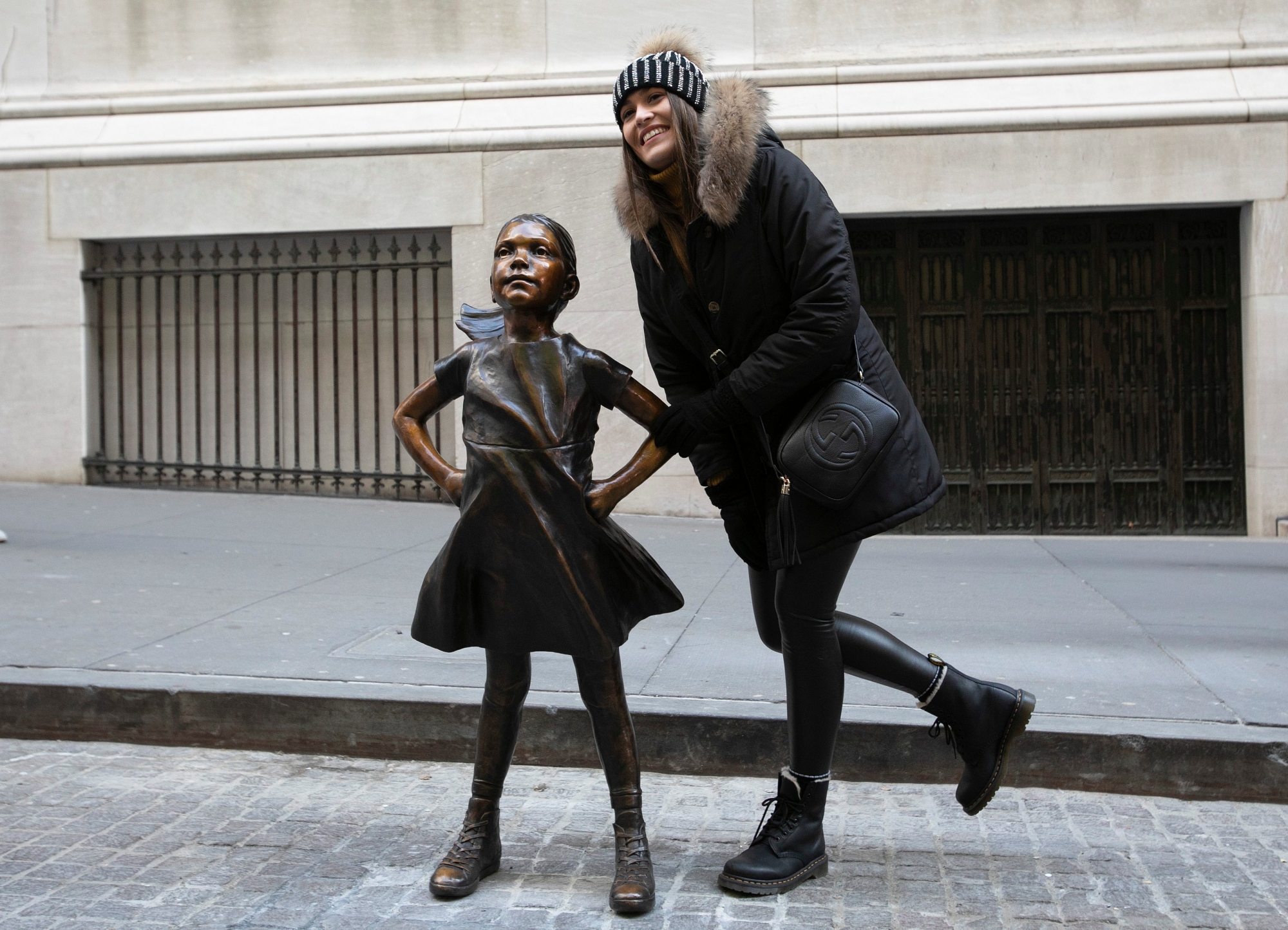 A woman poses with the "Fearless Girl" statue after it is unveiled at its new location in front of the New York Stock Exchange, Monday, Dec. 10, 2018, in New York. The statue, considered by many to symbolize female empowerment, was previously located near the Charging Bull statue on lower Broadway. (AP Photo/Mark Lennihan) FEARLESS GIRL