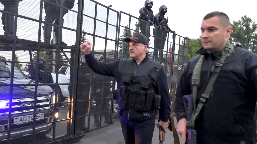 Cette image, réalisée à partir d'une vidéo fournie par la société nationale de télévision et de radio de Biélorussie, montre le président Alexandre Loukachenko armé d'un fusil de type Kalachnikov saluant les policiers anti-émeutes près du Palais de l'indépendance à Minsk.