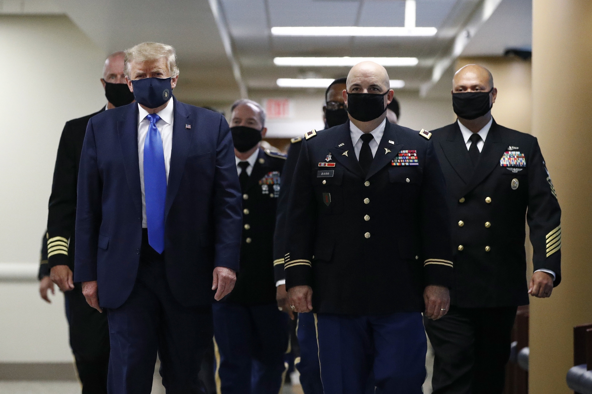 FILE - In this July 11, 2020, file photo President Donald Trump, foreground left, wears a face mask as he walks with others down a hallway during a visit to Walter Reed National Military Medical Center in Bethesda, Md. On Tuesday, July 21, Trump professed a newfound respect for the protective face masks he has seldom worn. ‚ÄúWhether you like the mask or not, they have an impact," he said. "I‚Äôm getting used to the mask,‚Äù he added, pulling one out after months of suggesting that mask-wearing was a political statement against him. (AP Photo/Patrick Semansky, File) Donald Trump ArcInfo