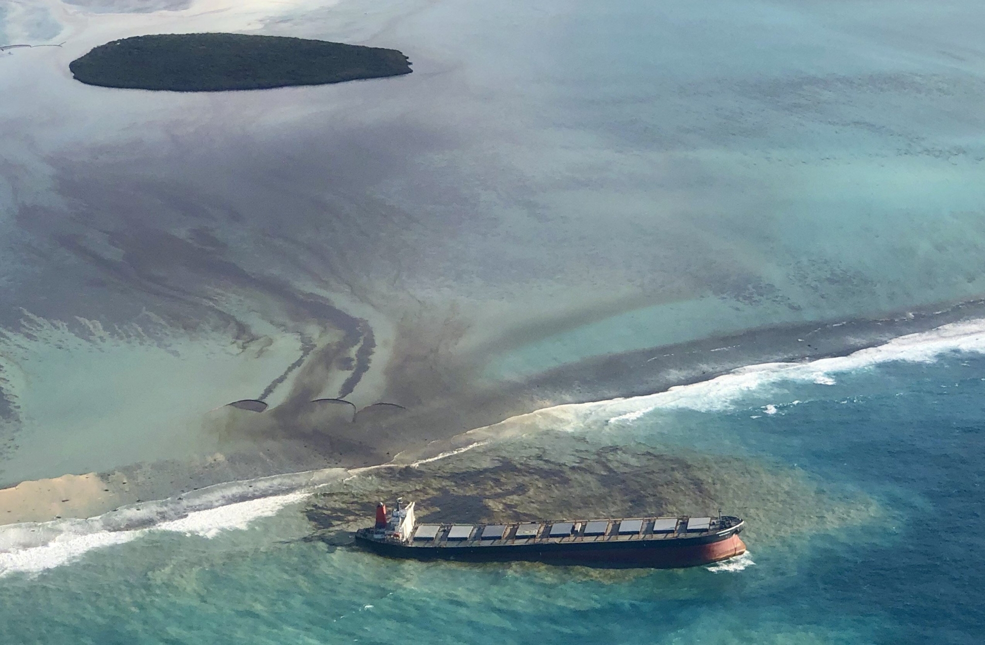 This photo taken and provided by Eric Villars shows oil leaking from the MV Wakashio, a bulk carrier ship that recently ran aground off the southeast coast of Mauritius, Friday, Aug. 7, 2020. Anxious residents of the Indian Ocean island nation of Mauritius are stuffing fabric sacks with sugar cane leaves to create makeshift oil spill barriers as tons of fuel leak from a grounded ship. The government has declared an environmental emergency and France says it is sending help from its nearby Reunion island. (Eric Villars via AP) ArcInfo