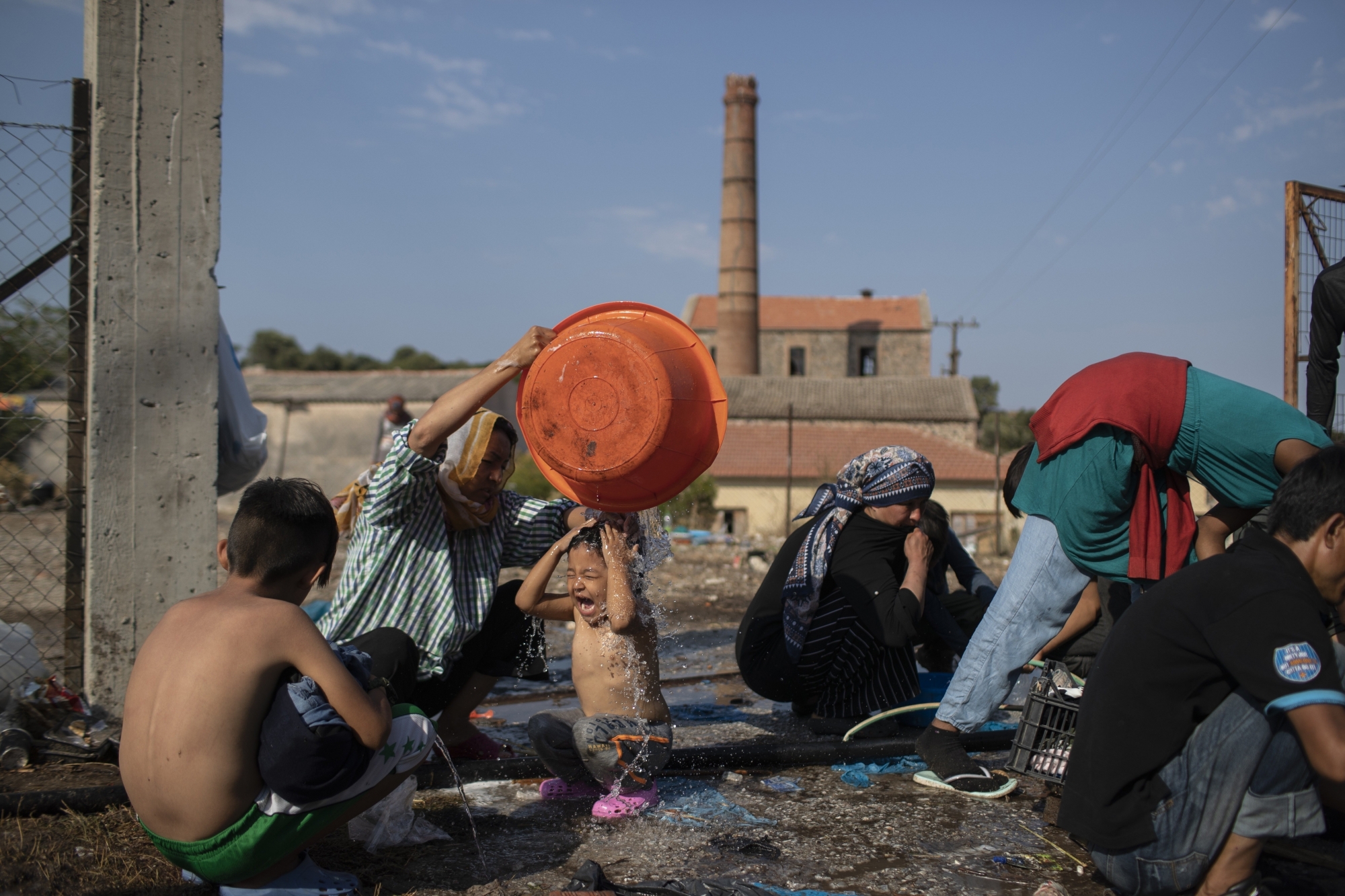 A woman washes a girl as migrants gather near Mytilene town, on the northeastern island of Lesbos, Greece, Saturday, Sept. 12, 2020. Greek authorities have been scrambling to find a way to house more than 12,000 people left in need of emergency shelter on the island after the fires deliberately set on Tuesday and Wednesday night gutted the Moria refugee camp. (AP Photo/Petros Giannakouris) ArcInfo